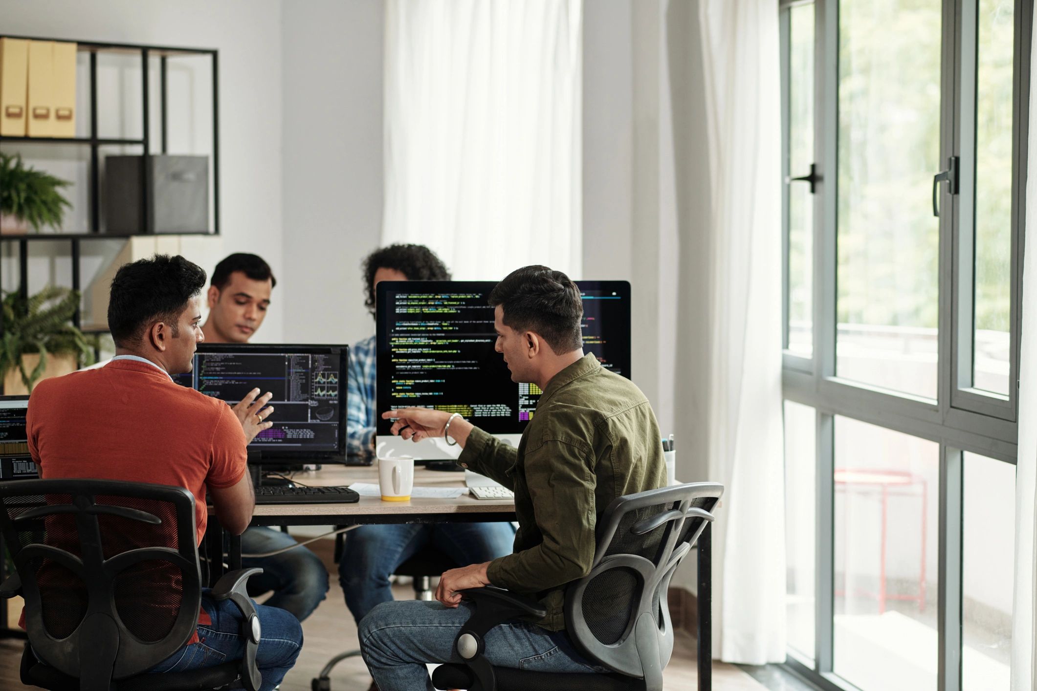 Software developers discussing programming code in an office